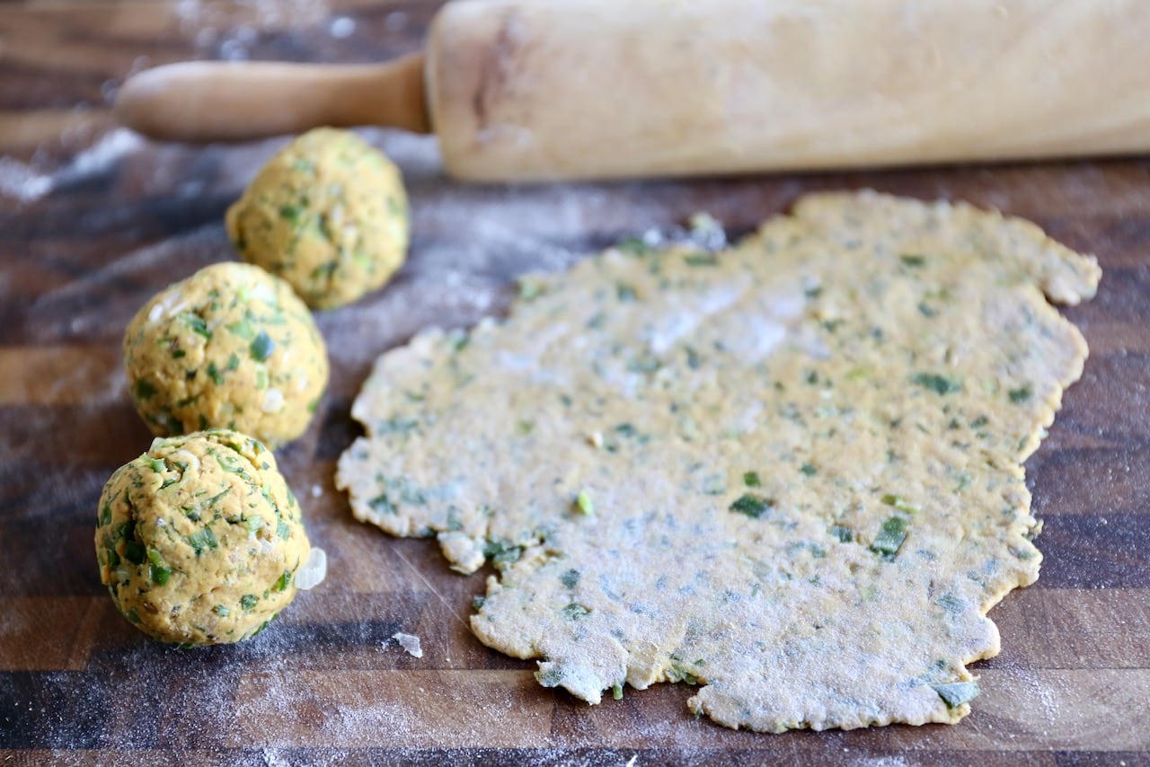 Divide the paratha dough into small balls before rolling out on a floured surface. 