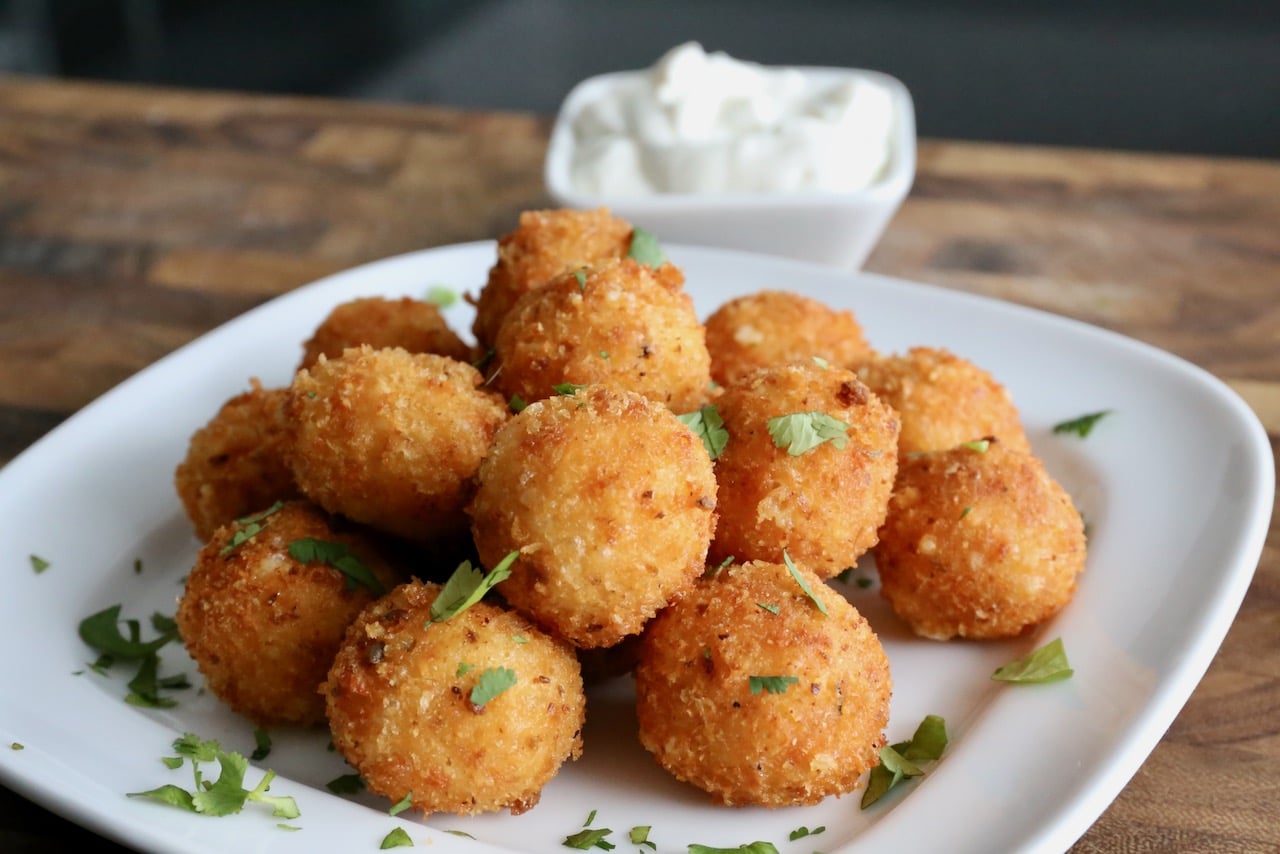 We like to serve Bolitas de Queso as a snack topped with chopped cilantro and dipped in sour cream.