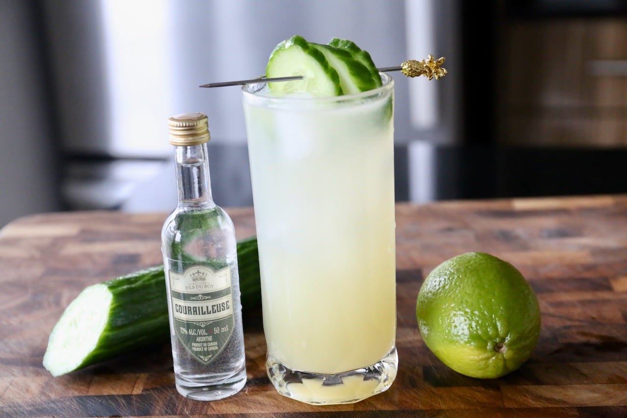 Ingredients are muddled together in a Collins glass showcasing a green hue. 