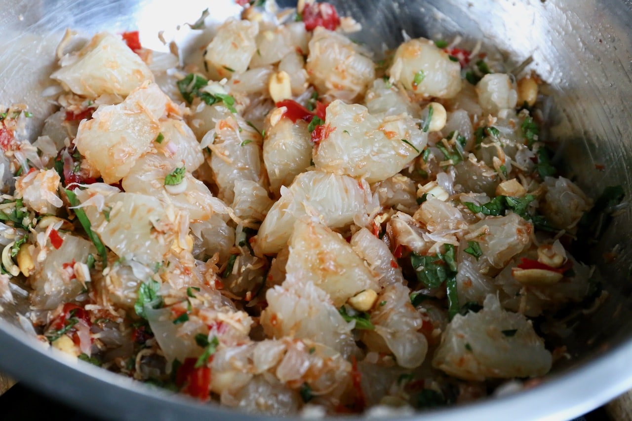 Toss Yam Som-O ingredients in a large salad bowl. 
