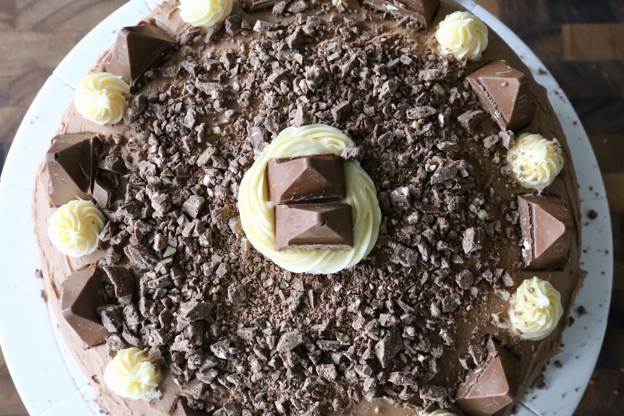 Top the cake with dollops of buttercream, chopped toblerone and toblerone pieces. 