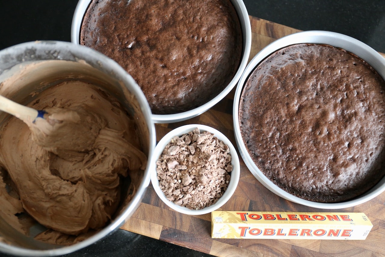 Create an assembly area on your counter with homemade icing, cake tins and chopped Toblerone.