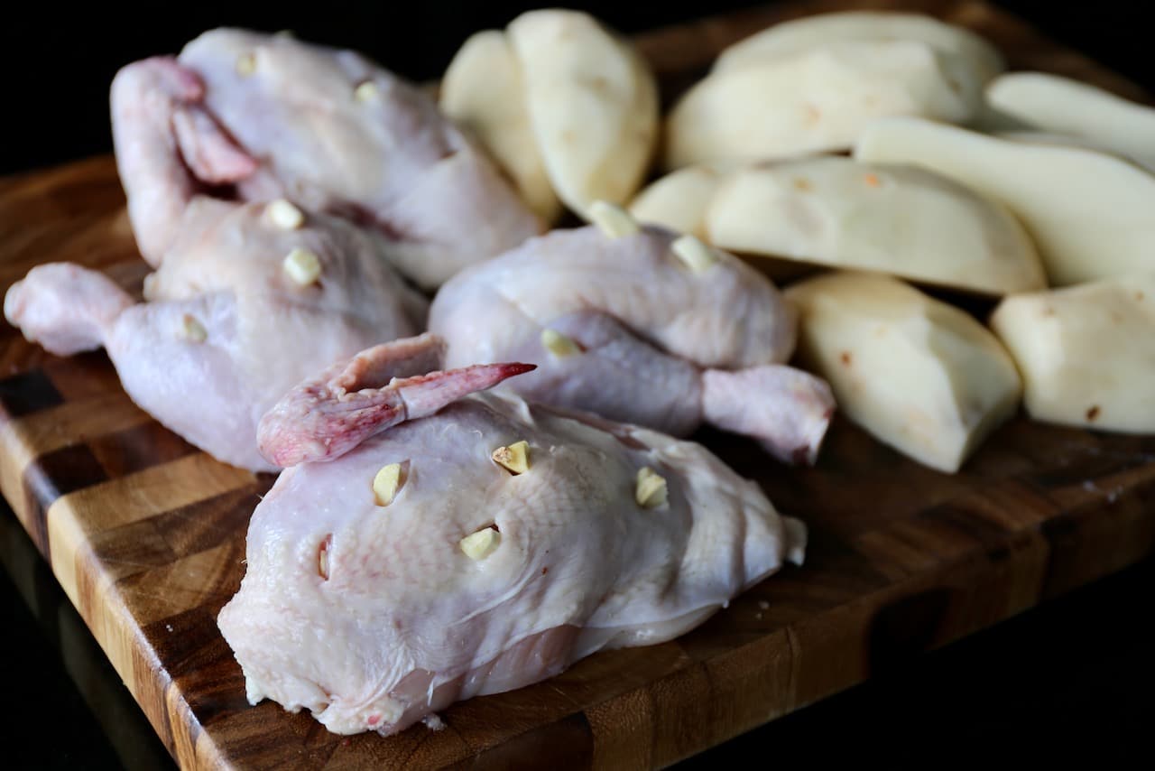 Break down the whole chicken into quarters and then pierce the skin with slivers of garlic.