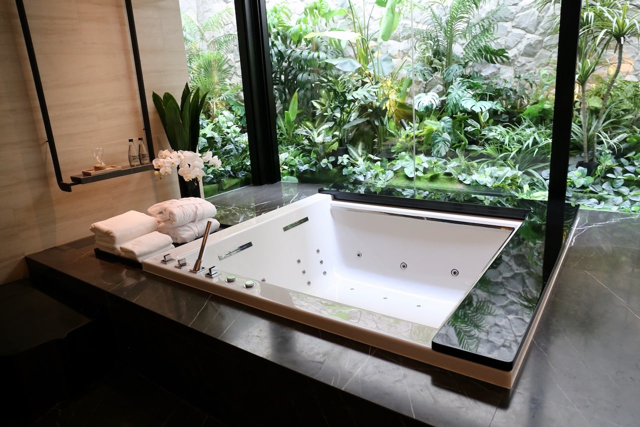 A romantic oversized jacuzzi tub overlooking a tropical garden in a Four Seasons Bangkok Spa Suite.