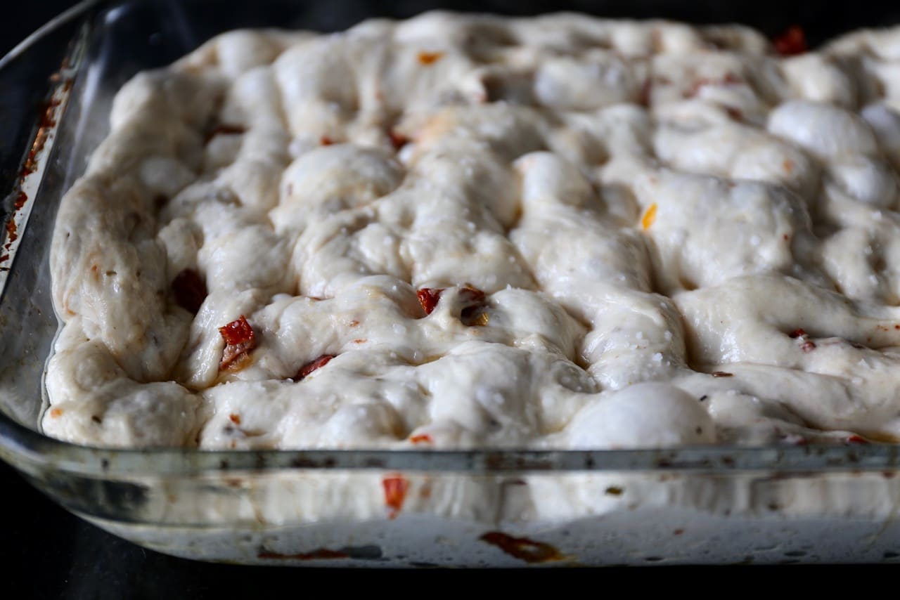 Stretch and dimple the dough in a baking pan then sprinkle with kosher salt before baking.