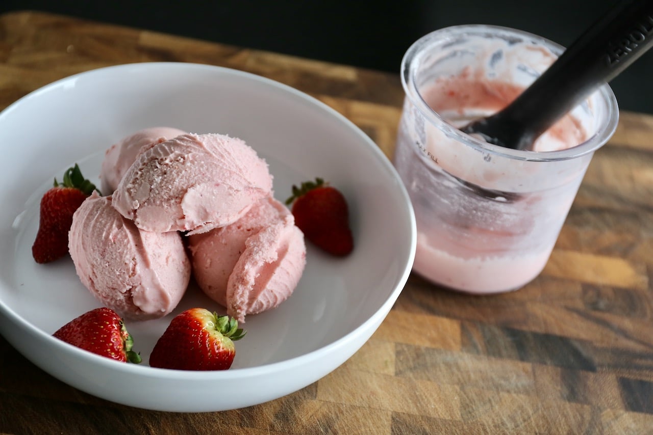 Scoop the Ninja Creami ice cream into bowls with fresh strawberries.