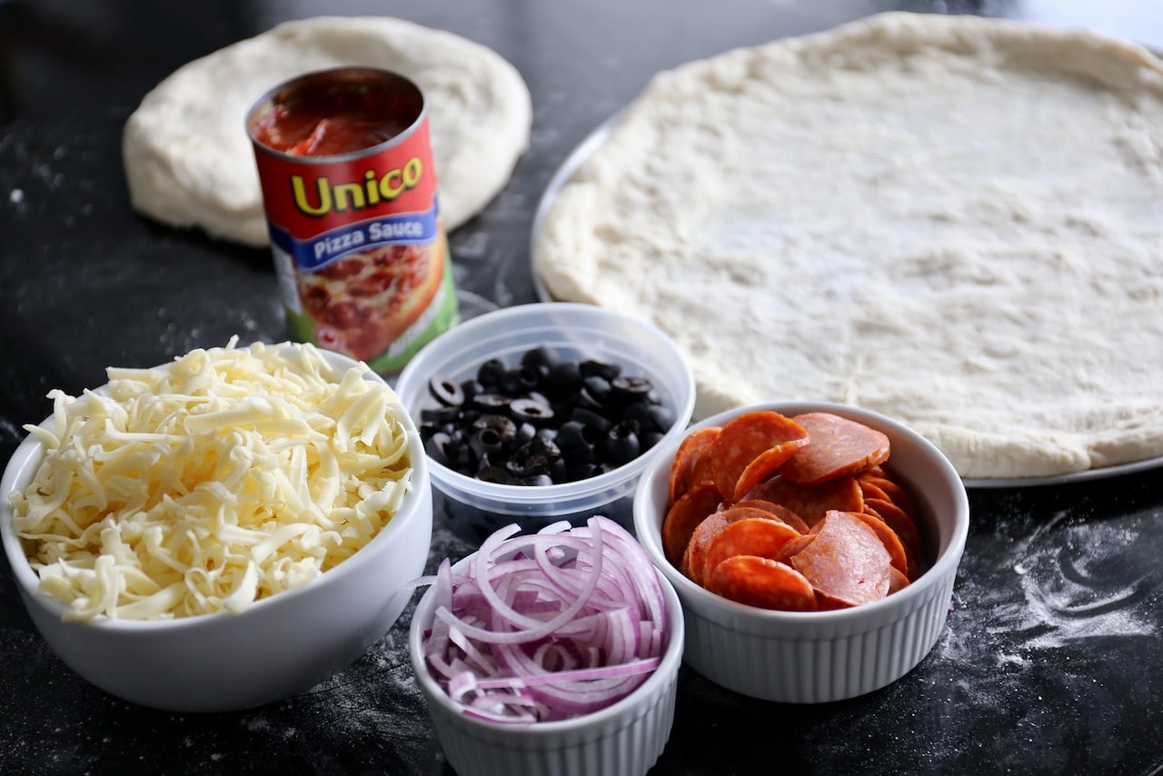 Top pizza dough with tomato sauce, shredded mozzarella and sprinkle with toppings.