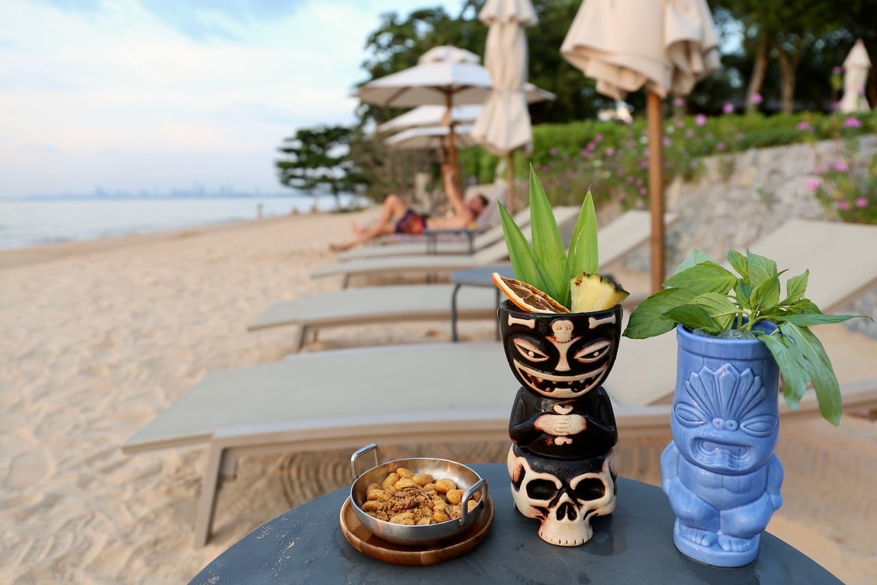 Order tiki cocktails with tom yum nuts on the beach at sunset. 