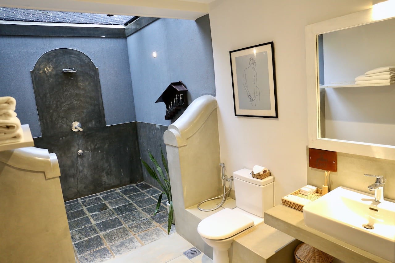 The bathroom features an outdoor waterfall shower.