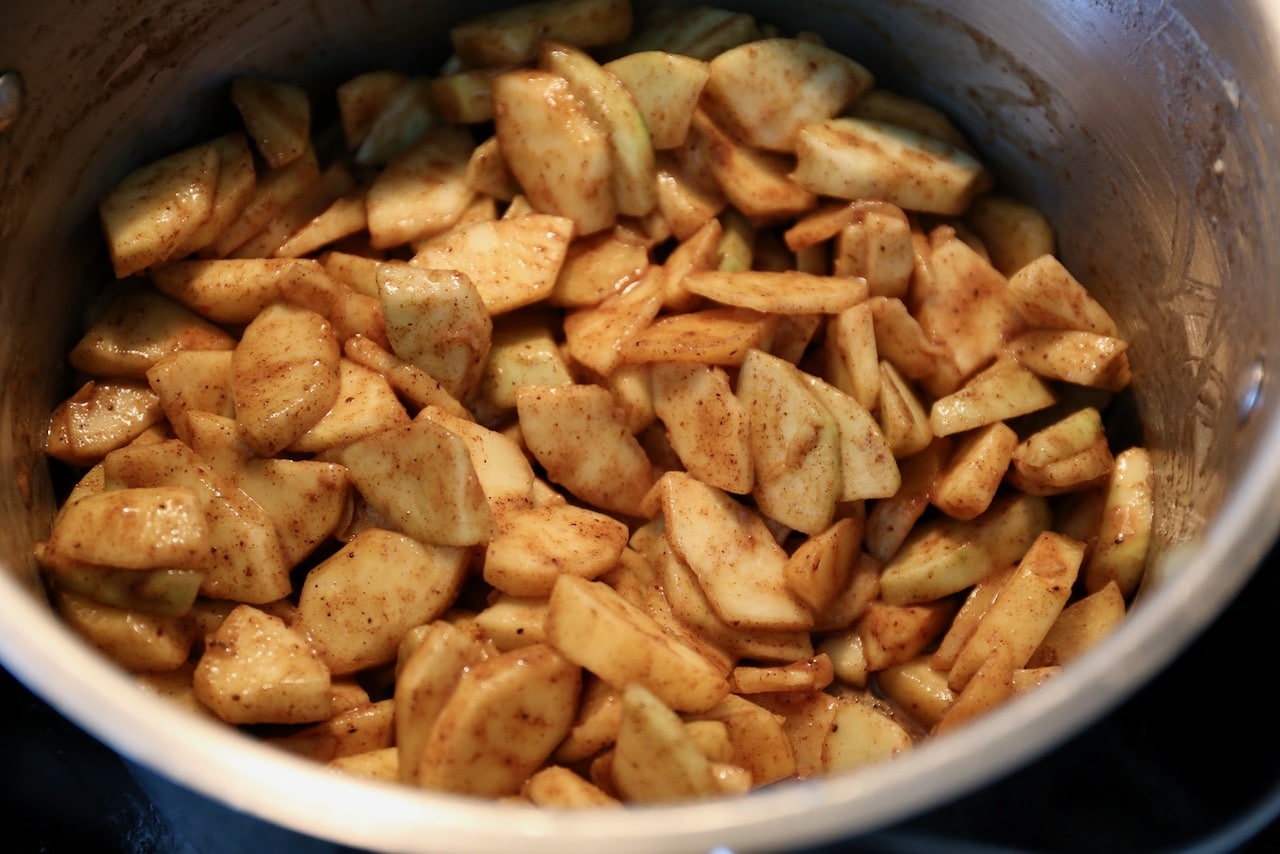Sautee sliced apples in a large pot with butter, lemon juice, and spices to soften them.