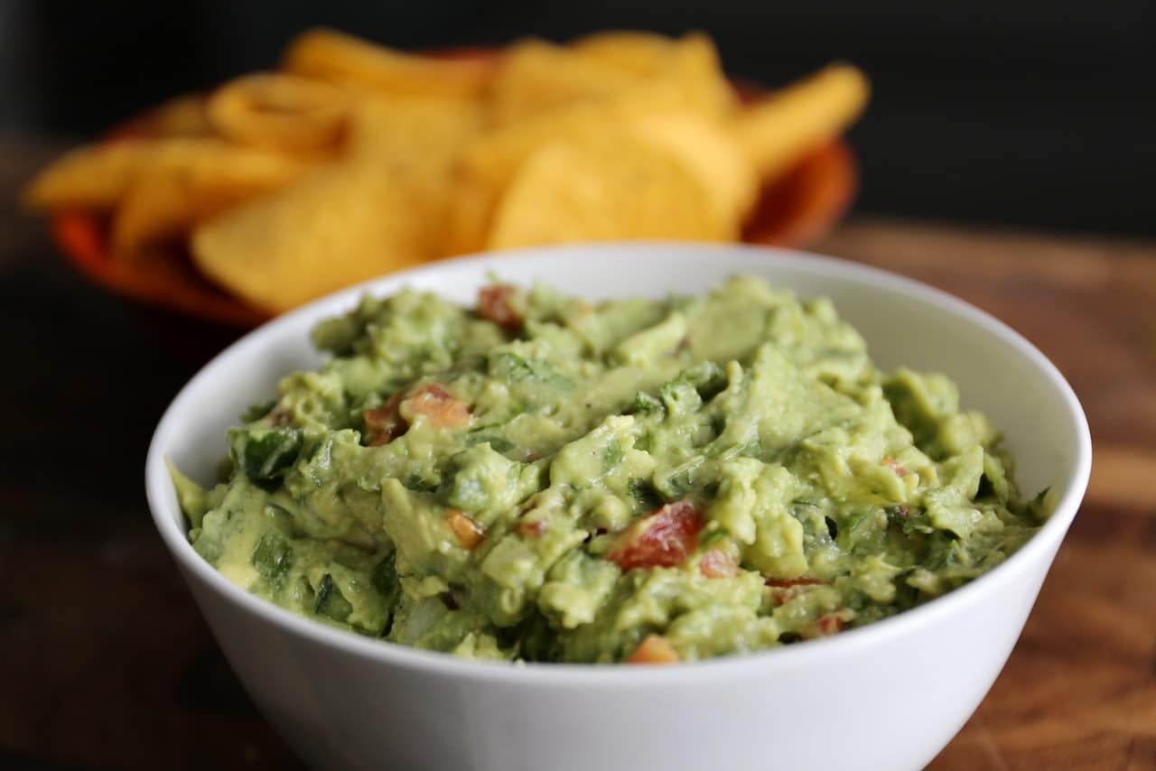 Serve homemade guacamole in a bowl with tortilla chips as a healthy snack.