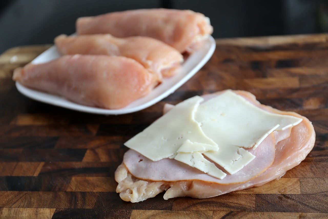 Butterfly chicken breasts and roll up with ham and Swiss cheese.