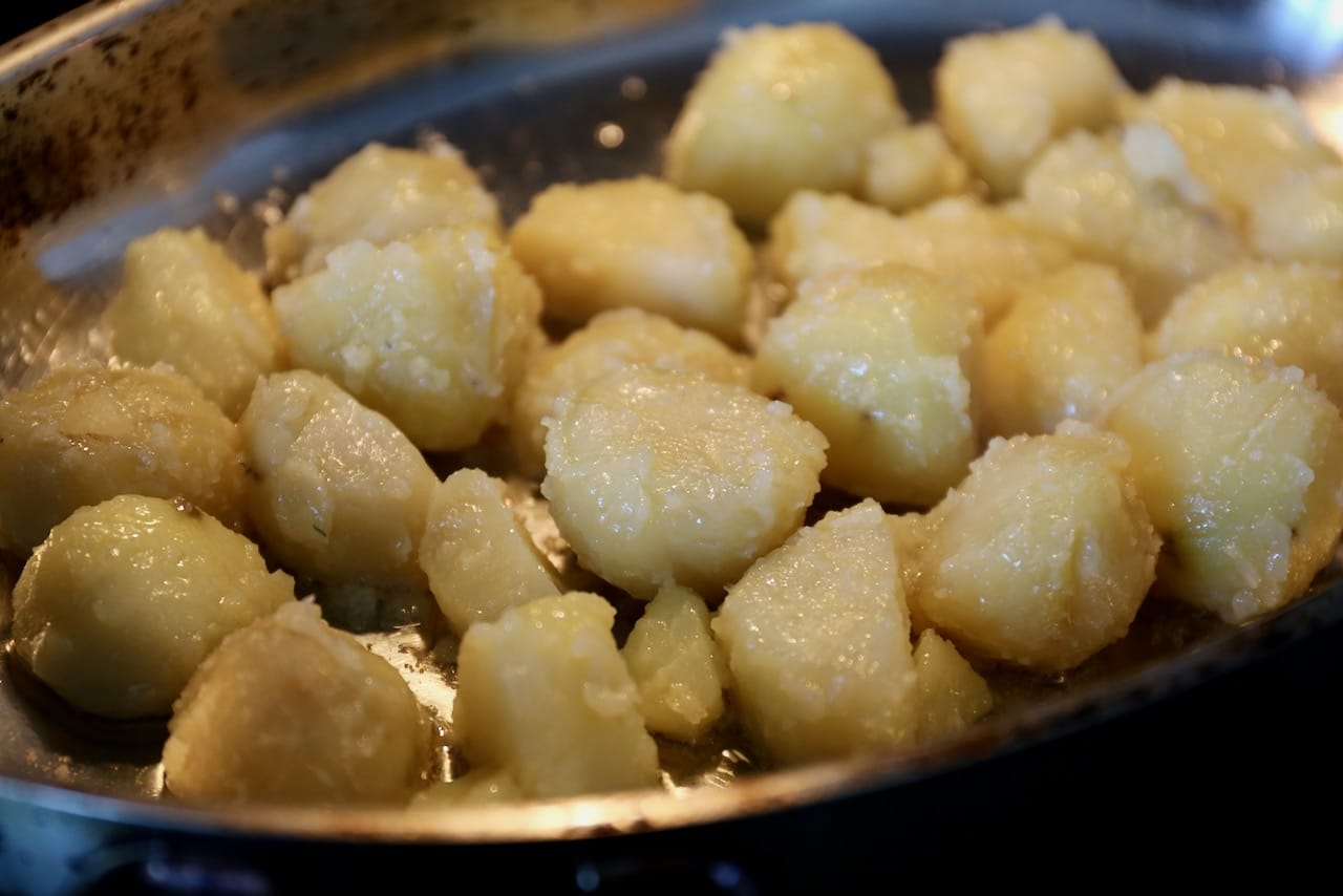 Shake boiled potatoes in a covered pot then toss in oil filled roasting pan.
